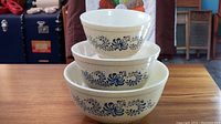 Stacked three bowl set showing beige speckled exterior with blue scroll and floral pattern on each bowl from the Homestead line by Pyrex