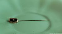Front view of the 14k white gold stick pin showing seed pearl and black stone