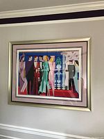 Framed abstract art print viewed frontally on the wall, showing the group of stylized figures and colors.
