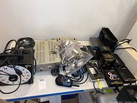 Photo of power supplies including Airpax ProPac series, Motorola radios, timer clock and adapters on a white table