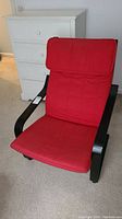 Front view of the black wooden armchair with red cushion, showing overall shape and cushion detail.