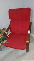 Front view of wooden armchair with red removable cushion.