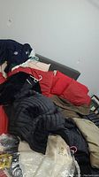 Image showing various jackets and blazers laid out on a couch and red cushions.