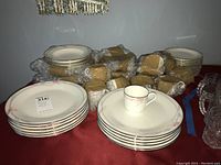 Full set of Mikasa bone china dinnerware displayed on a red surface, showing stacks of plates, bowls, cups wrapped in bubble wrap and paper for protection.