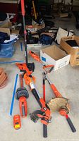 Photo showing the full collection of yard tools including hedge trimmer, edger, leaf blower, tamper, and wire cutters arranged on floor next to boxes.