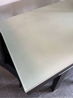 Close-up of the glass tabletop showing its surface condition and slight wear marks.