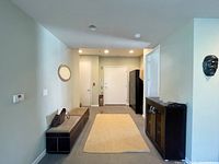 View of the bench placed in an entry hallway, showing cushioned top and overall size relative to surrounding space