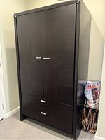 Front view of the wooden modern closet showing two doors with handles and two drawers below.