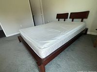 King size bed frame with mattress, showing wooden headboard and structure from side angle