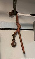Photo of a rust-colored metal chain binder with two hooks and a lever handle attached to a chain.