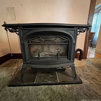 Front view of black cast iron gas log stove on tiled hearth