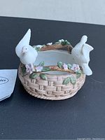 Lefton china decorative basket with two white birds perched on handle and rim, showing front angle with flowers and leaves detail