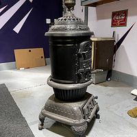 Front three-quarter view of potbelly stove showing cylindrical body, base and legs