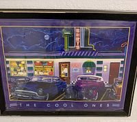 Framed poster depicting classic diner exterior with neon lights and vintage cars at night