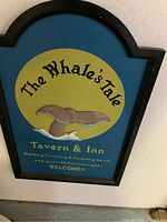 Framed wooden sign with whale's tail and text for The Whale's Tale Tavern & Inn