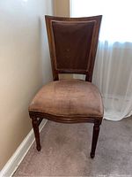 Side view of the upholstered seat and wood frame showing wear on the seat fabric and carved chair legs.