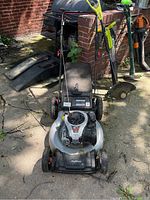 Front view of lawn mower showing black and silver body with Briggs & Stratton engine and attached grass catcher bag.