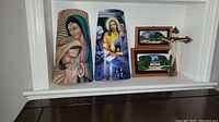 Group view of various religious art pieces including painted plaques and framed wall art