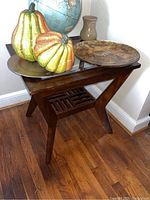 Two angled wooden side tables with glass inset tops, holding decorative items including a globe, gourds, and a vase, showing wood finish and table design