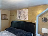 Wall decor on bedroom wall above headboard includes marbled canvas print, 'Live' metal sign, floral framed print visible to left
