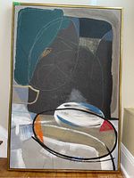 Full view of painting in gold metal frame leaning against wall