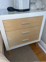 Front view of nightstand showing white frame and wood drawer fronts