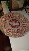 Single red and white transferware plate showing Greek key border and central chariot design