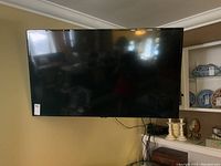 Front view of wall-mounted Samsung flat screen TV with power and signal cables hanging below