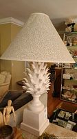 Full view of one lamp showing white ceramic artichoke base with conical patterned paper lampshade.