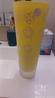 Yellow vase on bathroom sink, showing white swirl motifs on frosted yellow glass.