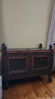 Full front view showing carved wood details, heavy corner posts with finials, and raised panels.