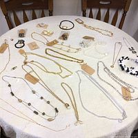 Wide view of varied costume jewellery spread out on a round table showing necklaces, bracelets, and rings in assorted styles and colors.