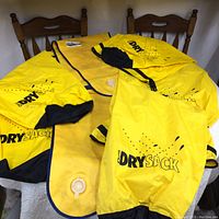 Overview of four yellow dry bags on chairs, including Coghlan's DrySack and Kodiak Sac dry bag with valve.