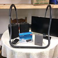 Lot displayed on round table showing Gateway LCD monitor, situp exerciser, speakers, and modem box