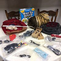 Photo showing collection including game box, backpacks, blanket, cables and accessories on white surface