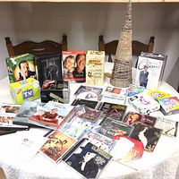 Full view of entertainment collection displayed on table including DVDs, CDs, and VHS tapes