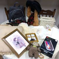 Overview shot of collection showing backpack, decorative root, plush toy, framed art, woven basket, UV-C sanitizer box, photo frame, pillow and ceramic item on a table.