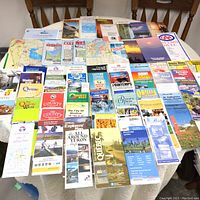 Photo showing a large assortment of Eastern Canada maps, city plans, and travel brochures spread out on a table.