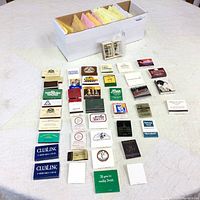 Overview of multiple matchbooks laid out, showing various colors and designs including advertising matchbooks and collectibles.