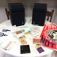 Pair of Bose 201 Series IV speakers on a table with guitar strings, rolled white item, and a red flag.