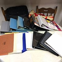 View of multiple binders, laptop case, duffle bag, and office supplies arranged on a table