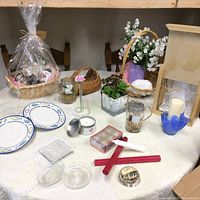 Photo of full lot on table showing gift basket, plates, candles, glassware and decor