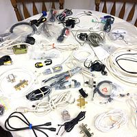 Spread out assortment of various cables and connectors on a flat surface including coaxial, serial, VGA and audio cables with some adapters and splitters.