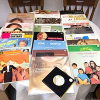 Photo showing multiple vinyl record albums arranged on a table including titles and artists such as Nana Mouskouri, Johnny Horton, and Mantovani.