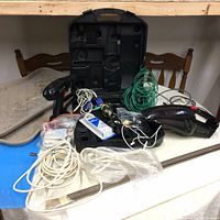 Includes jobmate cordless drill, carrying case, cables, and miscellaneous tools on table.