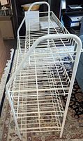 Side angled view of white wire shoe rack showing vertical supports and wire shelves