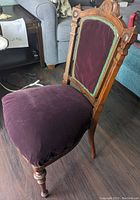Side and angled front view of antique wooden chair showing burgundy velvet upholstery and detailed carved wooden frame.