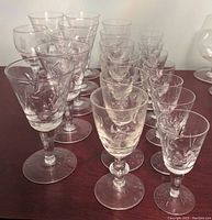 Grouped clear crystal glasses of varying styles showing etched and cut patterns on a wooden surface.