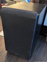 Black Infinity subwoofer with front fabric grille and woodgrain top finish.