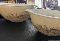 Close-up of two patterned ceramic mixing bowls with beige base and brown floral designs.